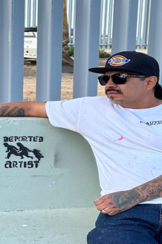 Man with mustache, sunglasses and cap leaning on painted bench by white railings