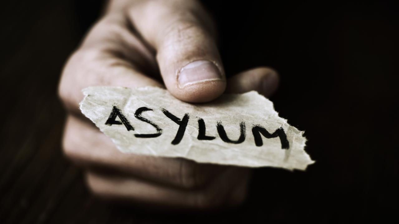Hand holding a note which reads "Asylum"