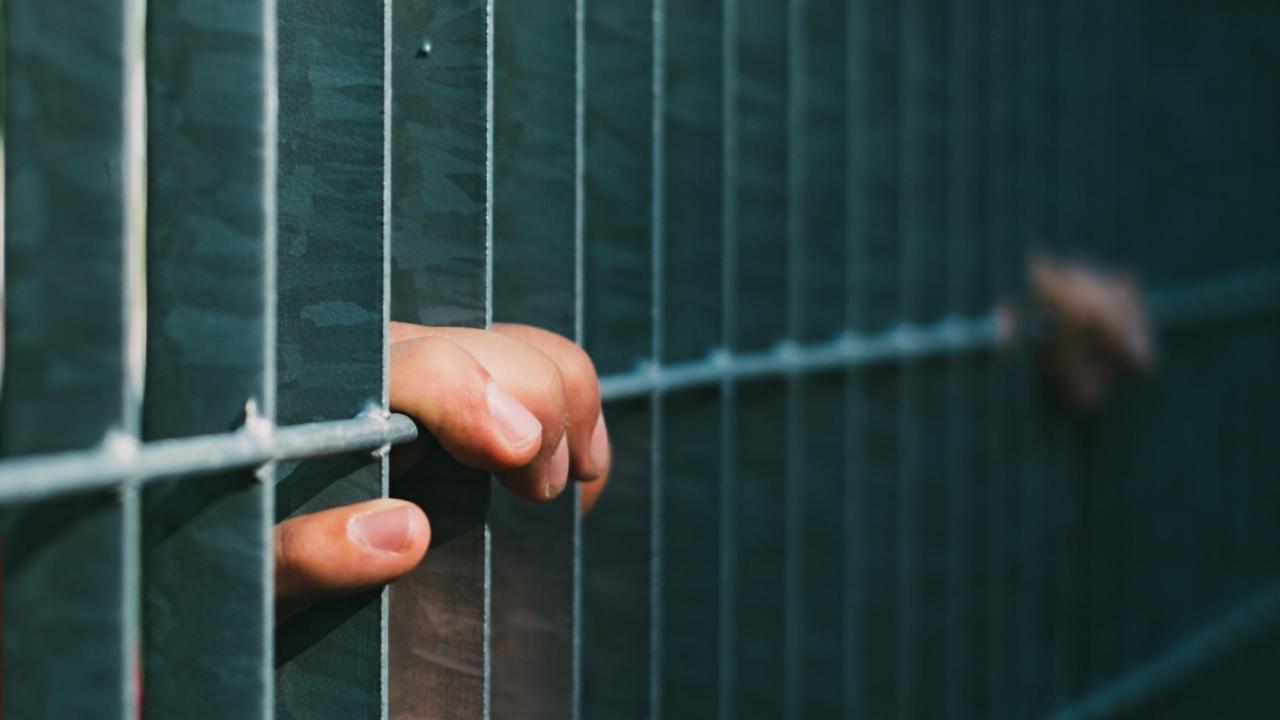 Hand grasping the edge of prison cell