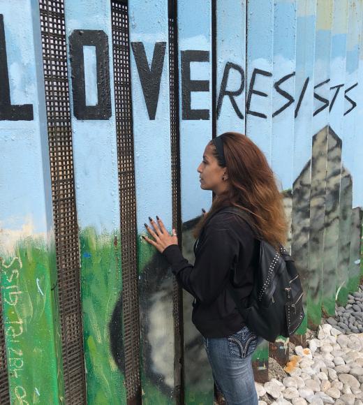 Woman staring at mural which reads "Love Resists"