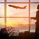 Person in airport looking at plane flying