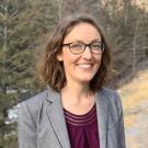 Smiling woman with glasses, shoulder-length hair and gray blazer in evergreen outdoors