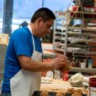 A Hispanic Immigrant kneading dough in a bakery