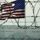 American flag behind barbed wire and fence