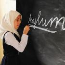 a girl writing asylum on a board 